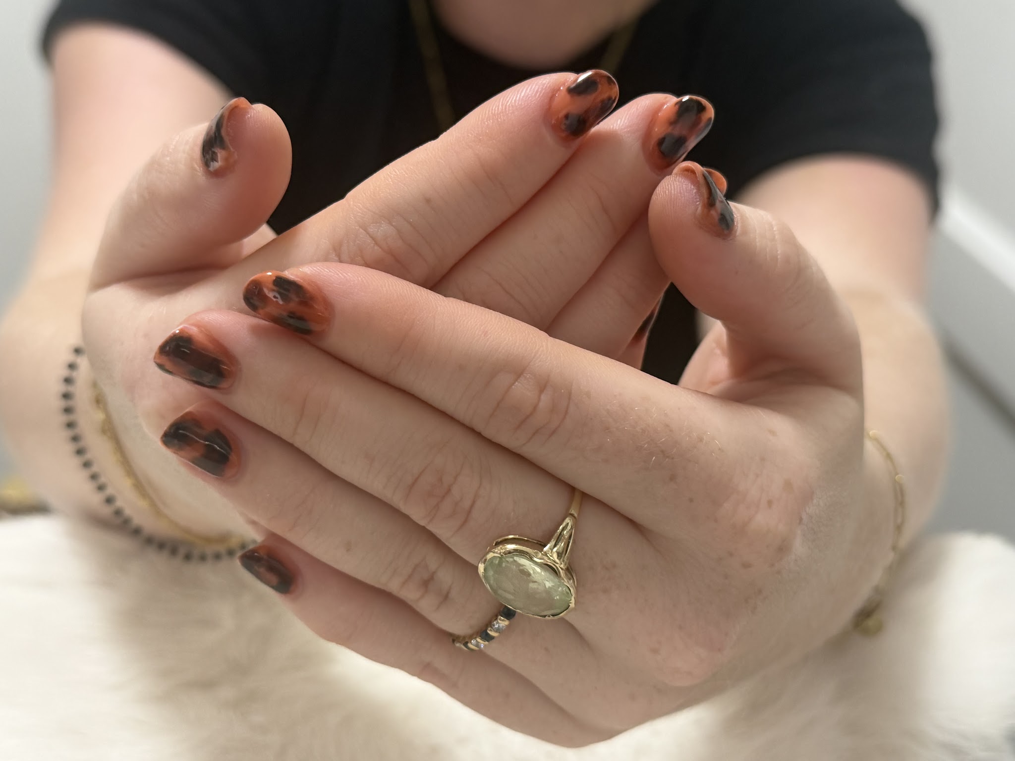 Handen met schildpadprint-nagels, gevouwen boven wit bont